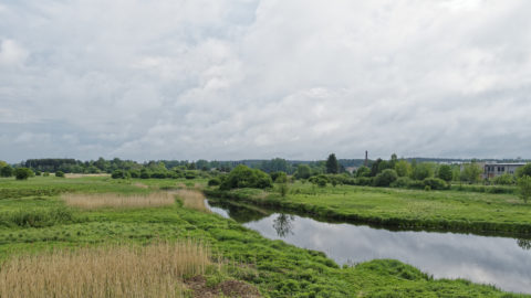 Bild: Blick in das Tal des Flusses Abava in Kandava in Lettland. Im Hintergrund sind verfallene Industriebetriebe zu sehen, die in Lettland bis heute allgegenwärtig sind.