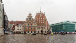 Bild: Auf dem Rathausplatz der Altstadt von Rīga. Von links nach rechts sind die Gebäude Speicher der Blauen Garde, das Schwabehaus und das Schwarzhäupterhaus zu sehen. Ganz rechts im Bild ist das gerade in der Rekonstruierung befindliche Lettische Okkupationsmuseum zu sehen.