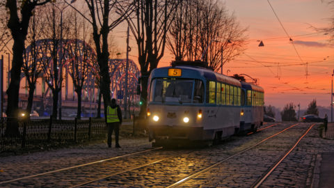 Bild: Sonnenuntergang an einem Novemberabend am Altstadtufer der Daugava in Rīga. Im Bild ist die Vorbereitung einer Fahrkartenkontrolle in einer Straßenbahn zu sehen. Fahrkartenkontrollen sind in Rīga immer generalstabsmäßig organisiert. Klicken Sie auf das Bild um es zu vergrößern.