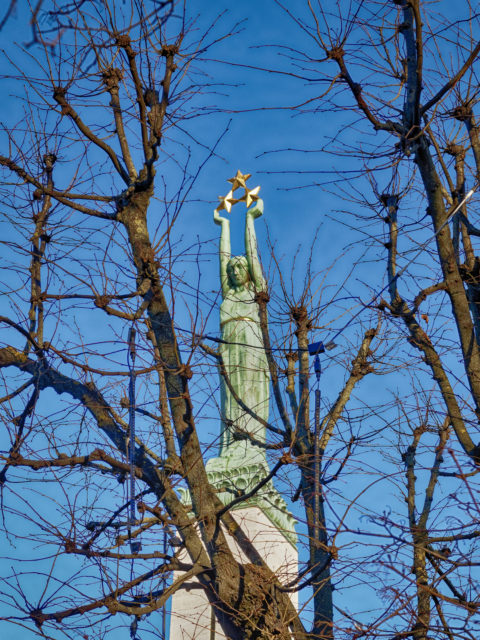 Bild: Das Freiheitsdenkmal - lettisch Brīvības piemineklis - auf dem Brīvības bulvāris in Rīga. Blick auf die Mädchenfigur Milda mit den drei Sternen, die die drei Regionen Lettlands - Vidzeme, Latgale und Kurzeme - symbolisieren. OLYMPUS PEN-F mit SIGMA 60 mm F2.8 DN ART - ISO200 ¦ f/5,6 ¦ 60 mm ¦ 1/800 s ¦ kein Blitz. Klicken Sie auf das Bild um es zu vergrößern.
